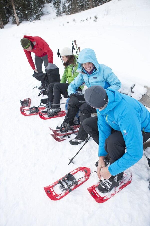 A group of people preparing snowshoes in a snowy outdoor setting.