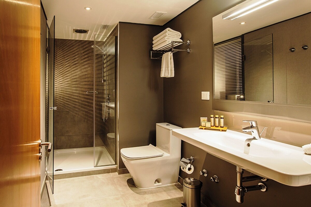 Une salle de bain moderne avec une douche à parois de verre, des toilettes, un meuble-lavabo et un miroir.
