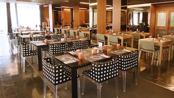 Un restaurante con varias mesas y sillas, dispuesto en un espacio amplio.