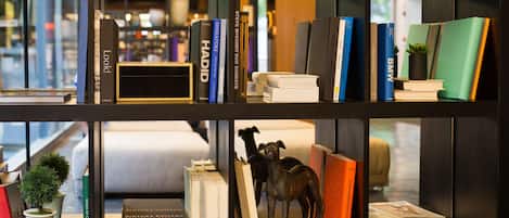 A bookshelf with books, a small potted plant, and a decorative dog statue.