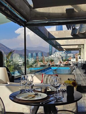 Un área de comedor en la azotea con vistas a un paisaje urbano y montañas.