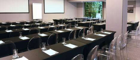 A conference room with multiple tables, chairs, and a projector screen.