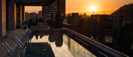 Una piscina en la azotea con vistas a la ciudad al atardecer.