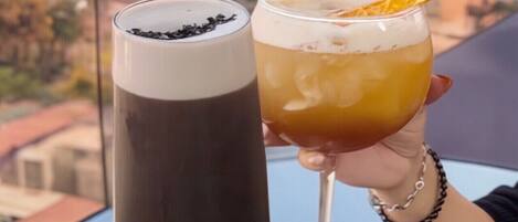 Dos bebidas sostenidas por una persona, con un paisaje urbano al fondo.
