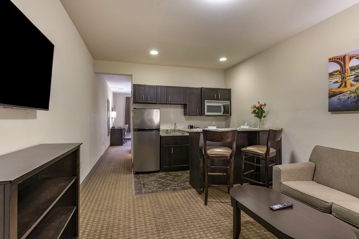 A compact living space with a kitchenette, a flat-screen TV, a sofa, and a coffee table.