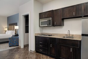A modern kitchen with dark cabinetry, a built-in microwave, and a stainless steel refrigerator.