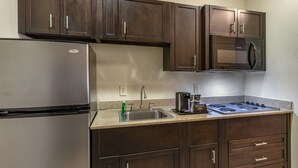 Une cuisine avec des meubles en bois foncé, un réfrigérateur en acier inoxydable, un four à micro-ondes, un évier et une cuisinière à gaz.