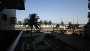 A residential area with a view of the beach, palm trees, and parked cars. - Lucio Costa 103 (Rio de Janeiro)