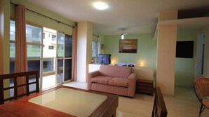 A living room with a wooden table, a pink sofa, and a television. - Lucio Costa 103 (Rio de Janeiro)