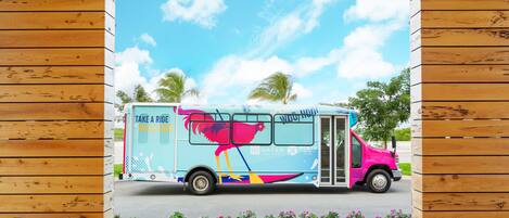 A colorful bus with a tropical design parked in front of a wooden structure.