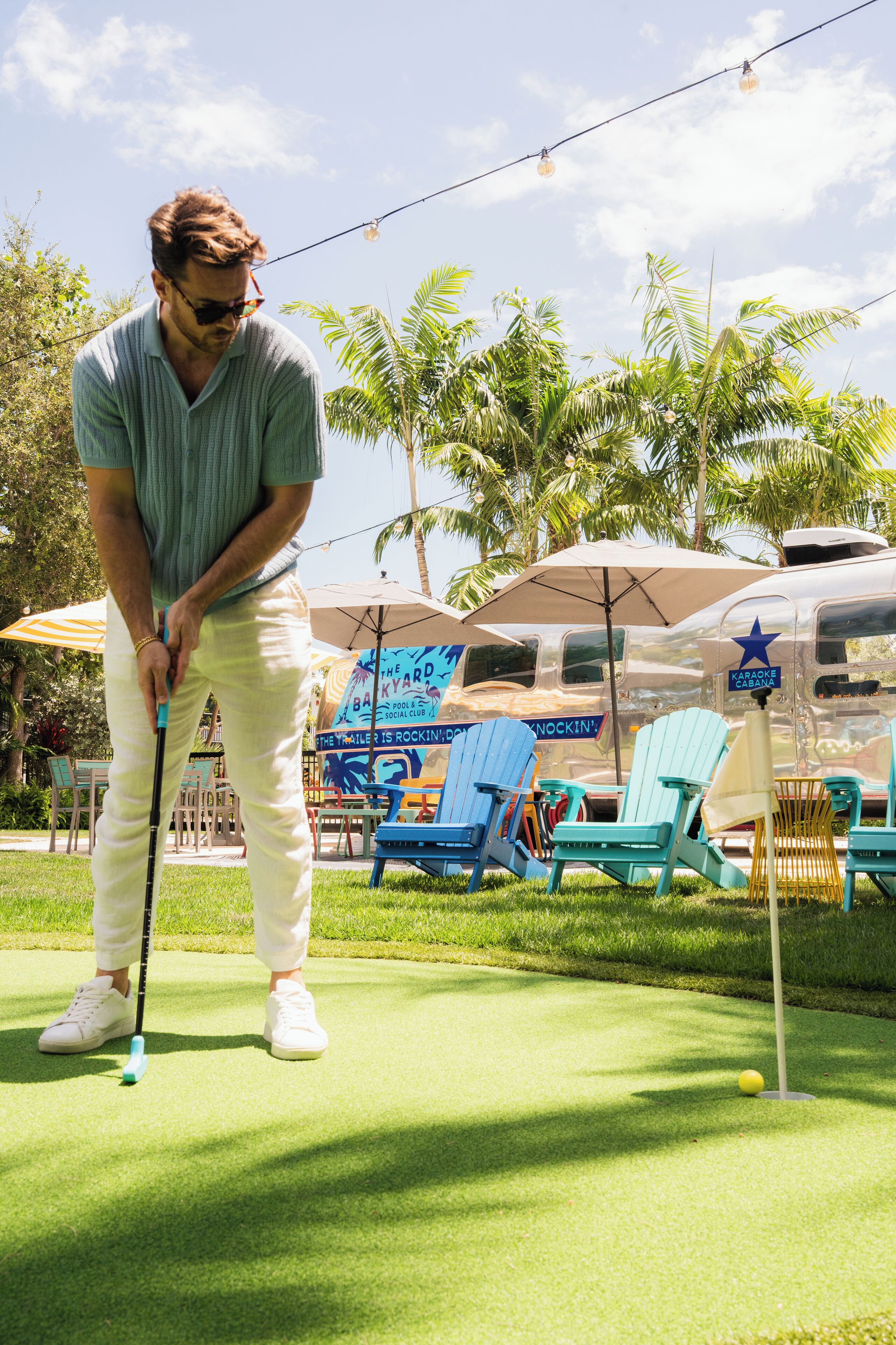 A person playing golf on a green with a putting cup and a golf ball.