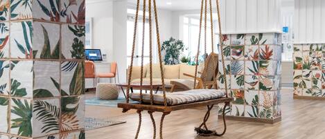 A spacious living area with a wooden swing chair, a sofa, and a coffee table.