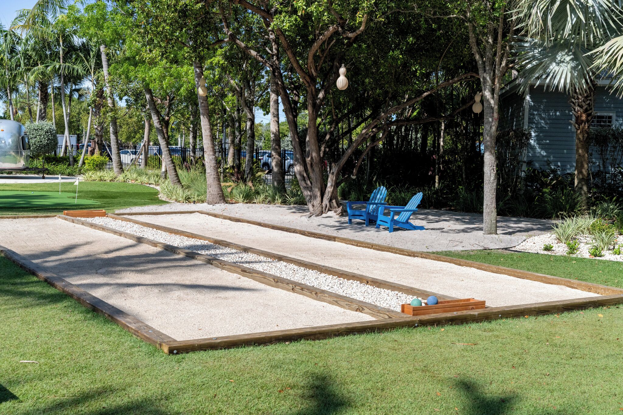 Shuffleboard-pelikenttä, jossa on puinen kehys, sininen tuoli ja taustalla palmu.