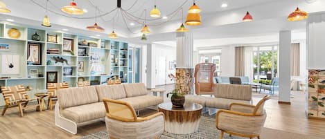 Amplia sala de estar con sofá, sillones y una mesa de centro, con una estantería y objetos decorativos.