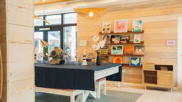 A room with a wooden wall, a table with a dark tablecloth, and shelves with various items.