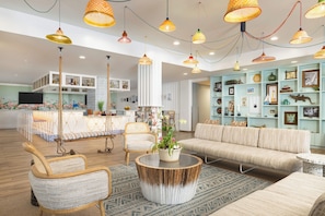 Un grand salon comprenant un canapé, des fauteuils, une table basse et un fauteuil suspendu.