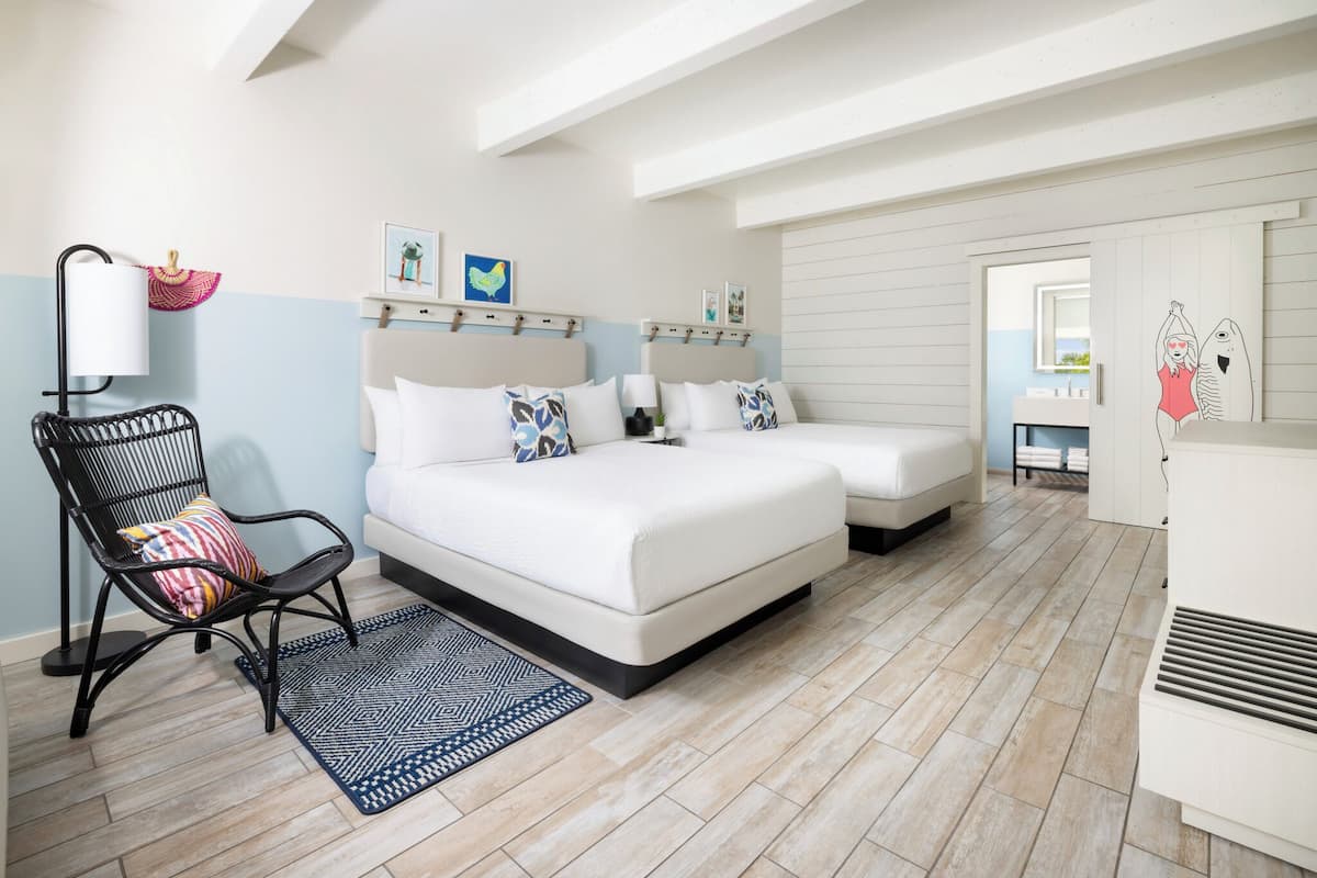 A bedroom with a bed, two bedside tables, a chair, a lamp, and a rug.