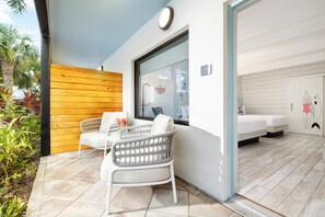 A modern room with a wooden wall, a large window, a white sofa, and a wicker chair. - Blue Flamingo Resort Key West (Key West)