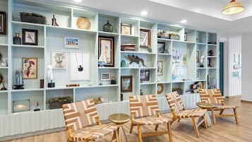 A room with a light blue wall, wooden floor, and a seating area with patterned chairs and a small round table.