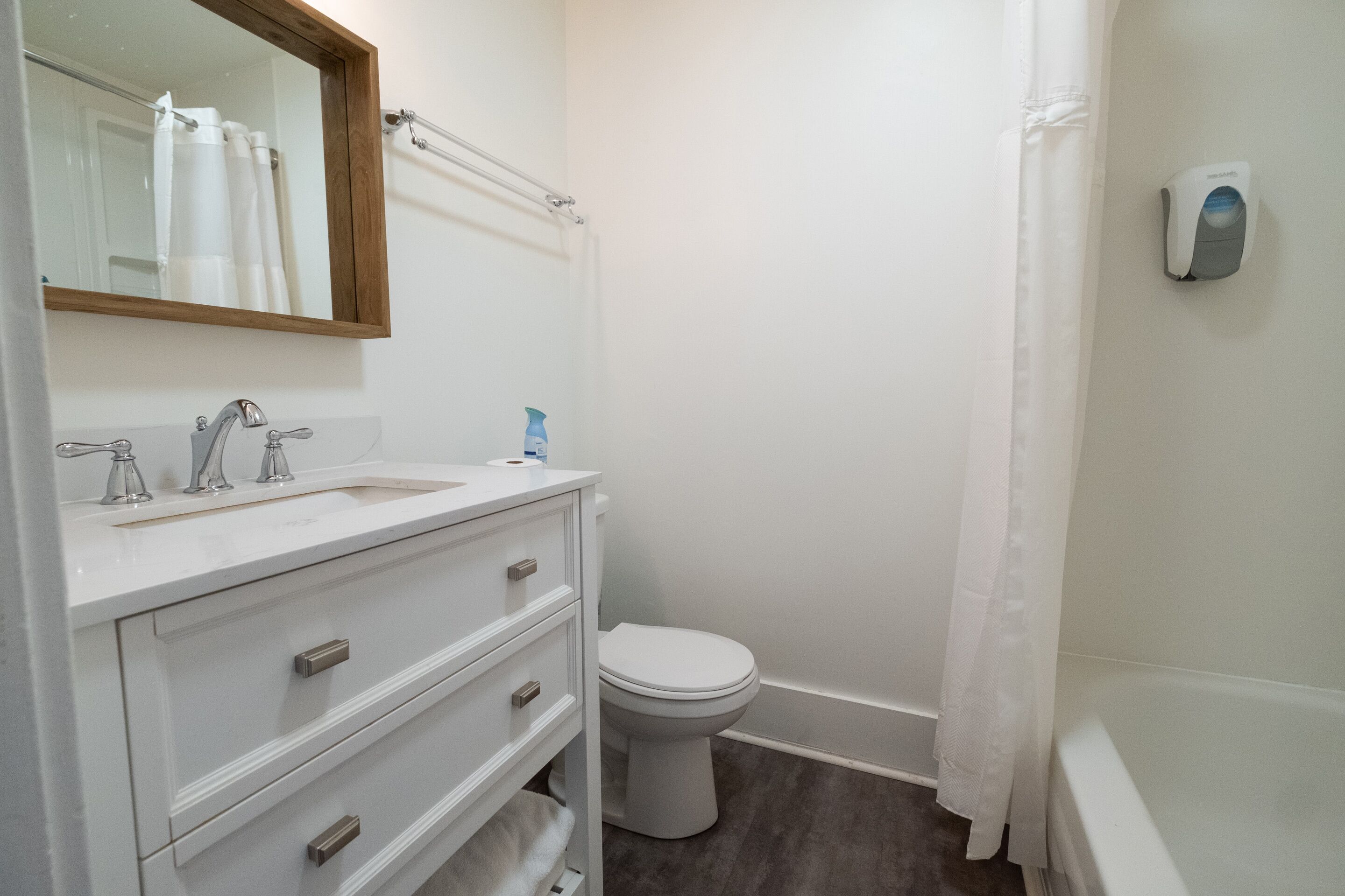 A bathroom with a white vanity, a toilet, and a bathtub.