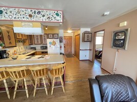 Una cocina con una isla central, sillas de madera, un refrigerador y un microondas.
