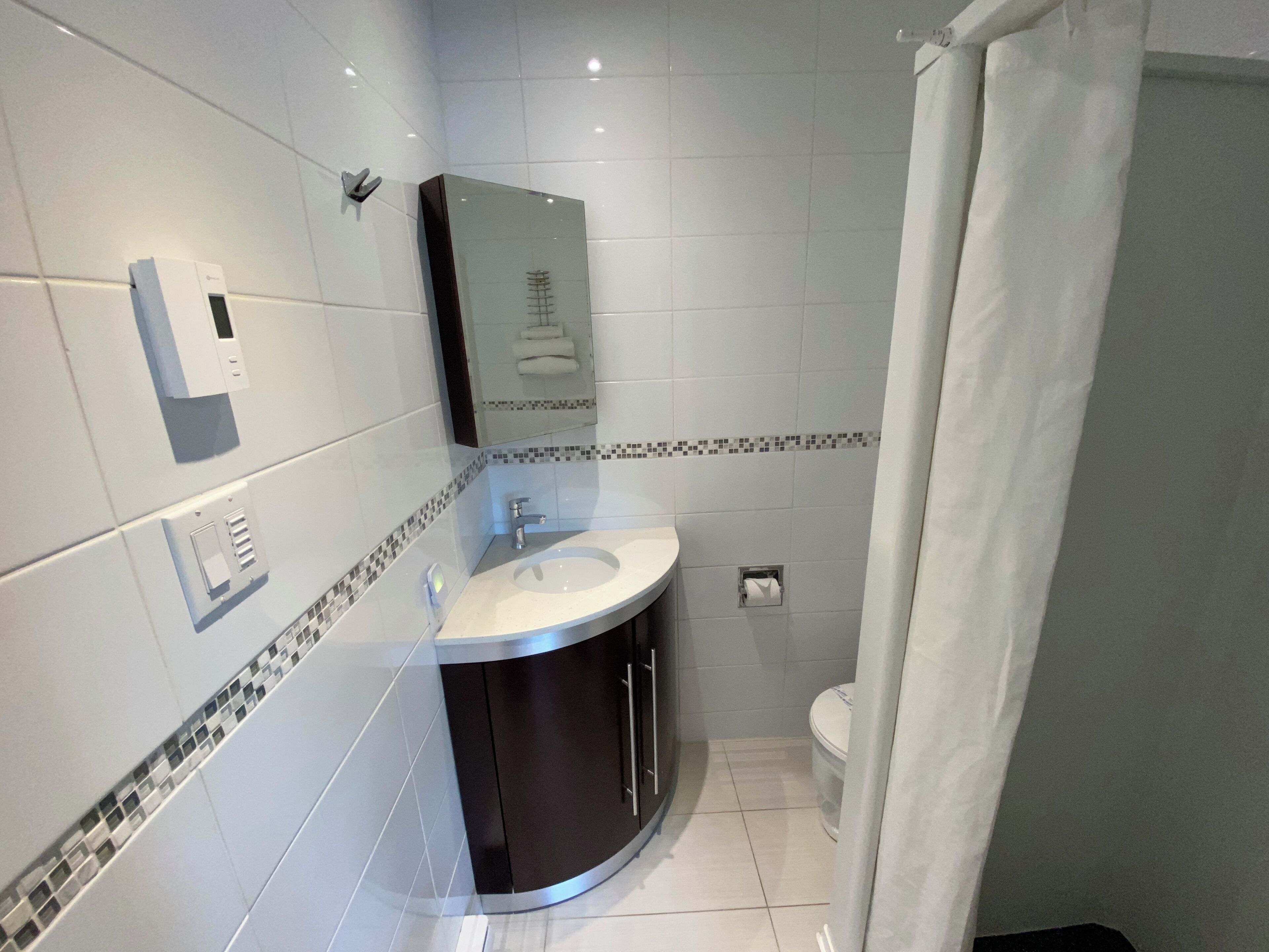 Un baño moderno con un lavamanos blanco, un espejo y un inodoro.