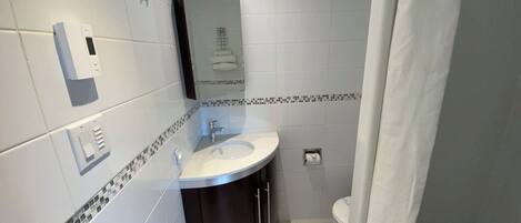 A modern bathroom with a white sink, a mirror, and a toilet.