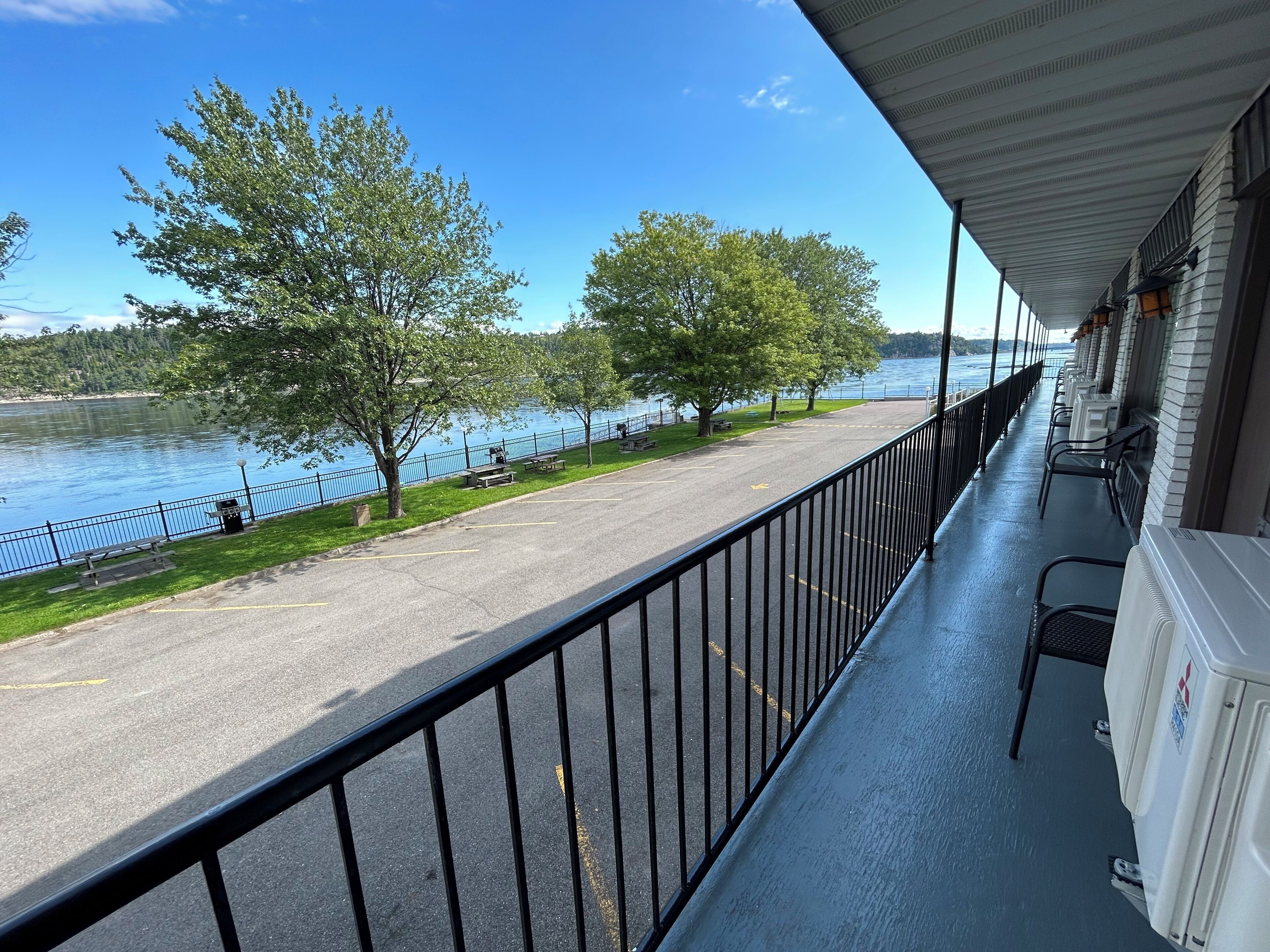 Un balcon donnant sur un lac, des bancs et une allée pavée.