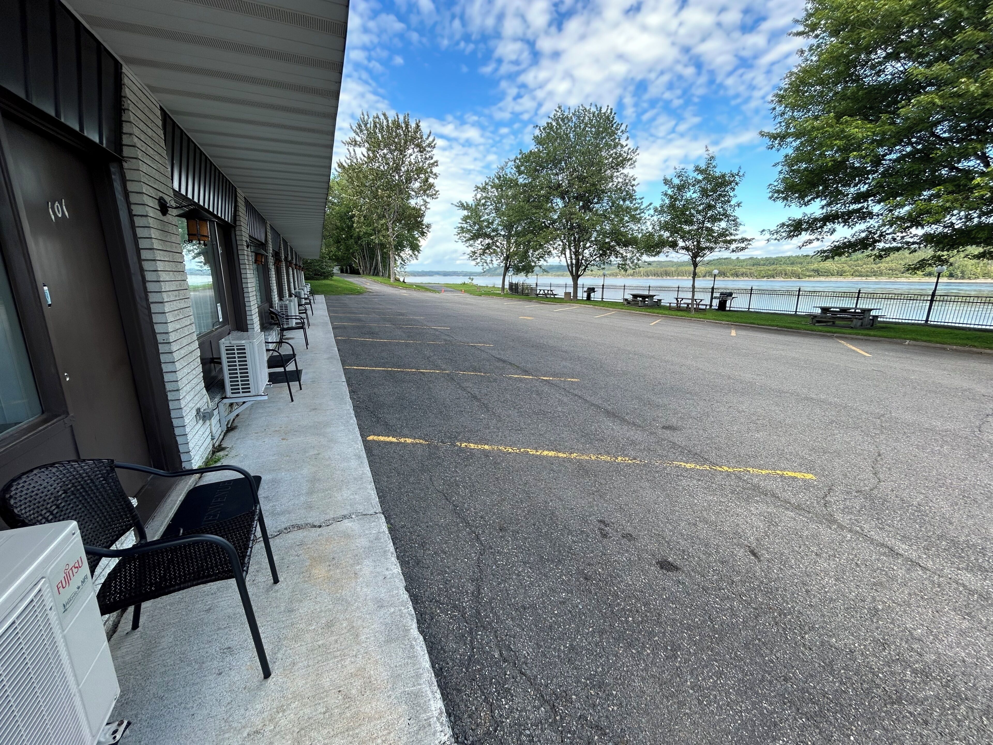 Un parking avec une rangée de sièges en plein air et un bâtiment sur lequel on peut voir le numéro « 101 ».