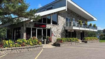 Un motel appelé « Panoramique », doté d’une façade en pierre, de grandes fenêtres et d’un balcon agrémenté de jardinières suspendues.
