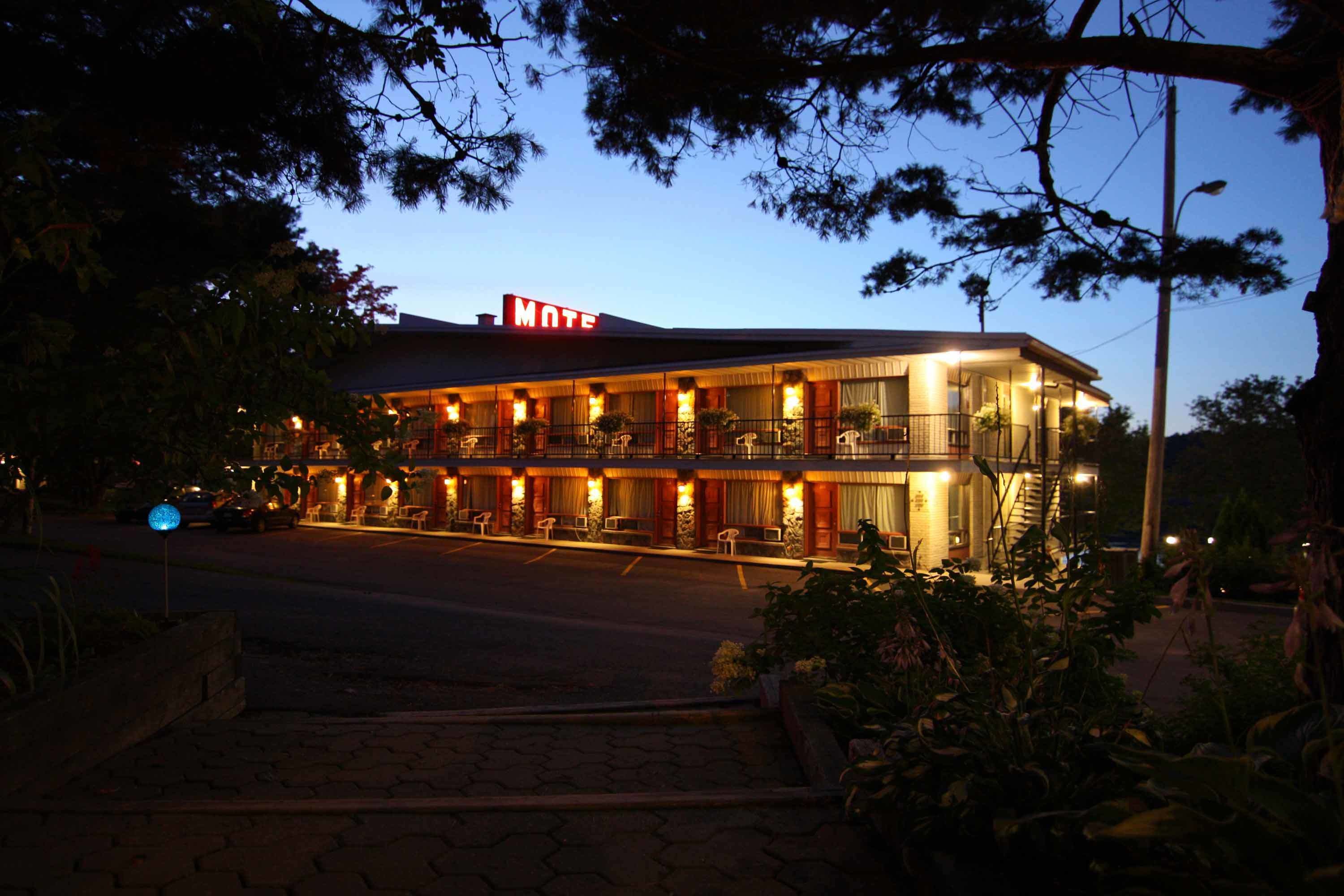 Ein Motel mit zweistöckigem Bau, einer auffälligen Neonreklame und einem gut beleuchteten Eingang.