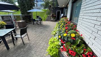 Un pati amb paviment hexagonal, mobiliari exterior i una jardineria.
