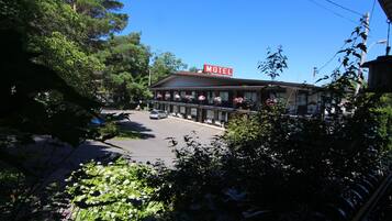 A motel with a signboard, a parking lot, and surrounding greenery.