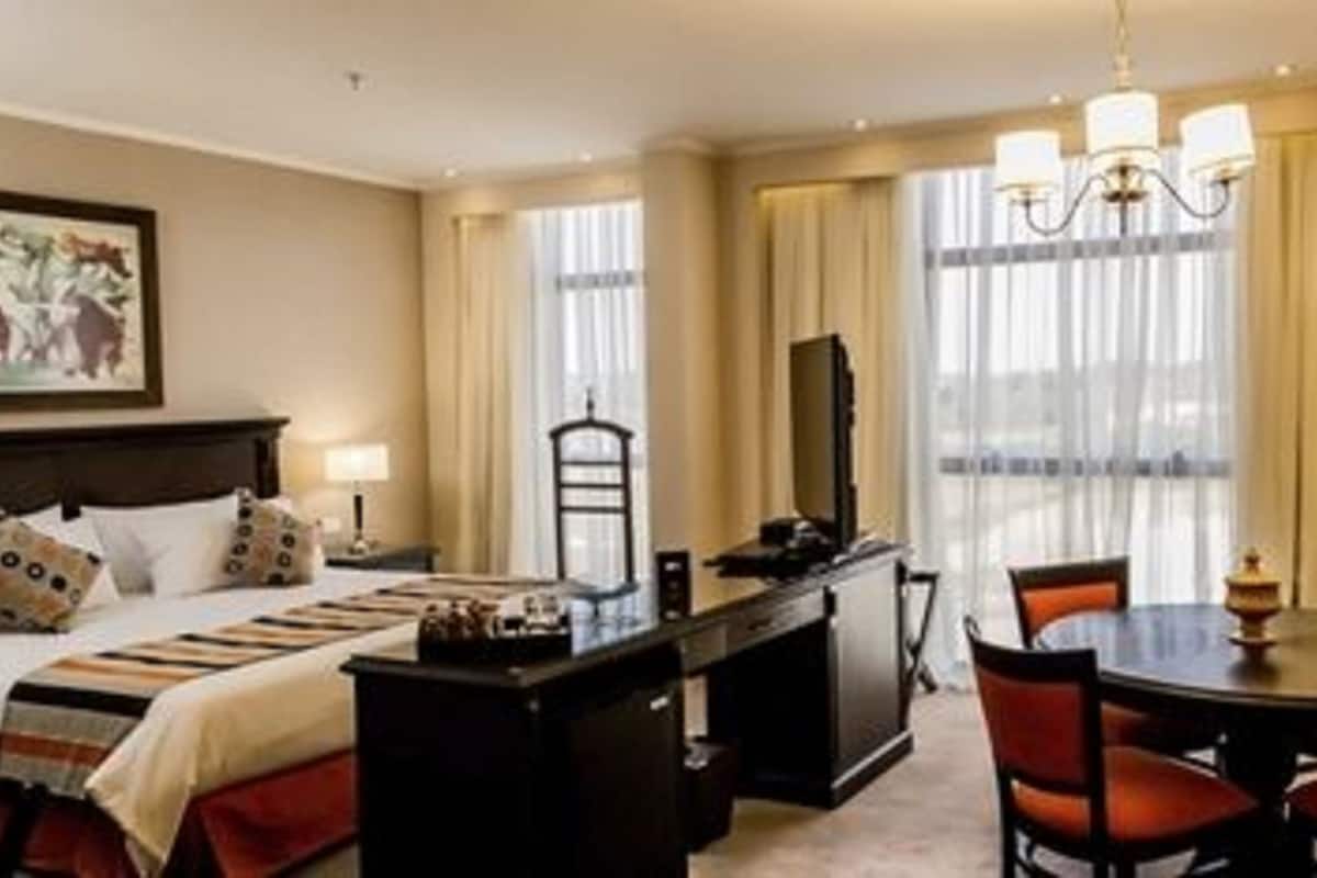 A hotel room with a bed, desk, chairs, and a dining table.