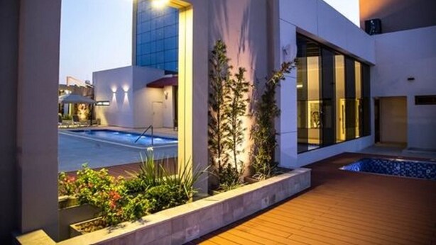 A modern building with a swimming pool, large windows, and a wooden deck. - Carnaval Hotel Casino (Encarnacion)
