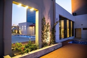 A modern building with a swimming pool, large windows, and a wooden deck. - Carnaval Hotel Casino (Encarnacion)