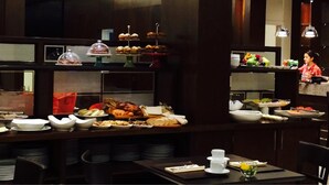 A buffet setup with various food items, including pastries and fruits, and a person in the background. - Carnaval Hotel Casino (Encarnacion)