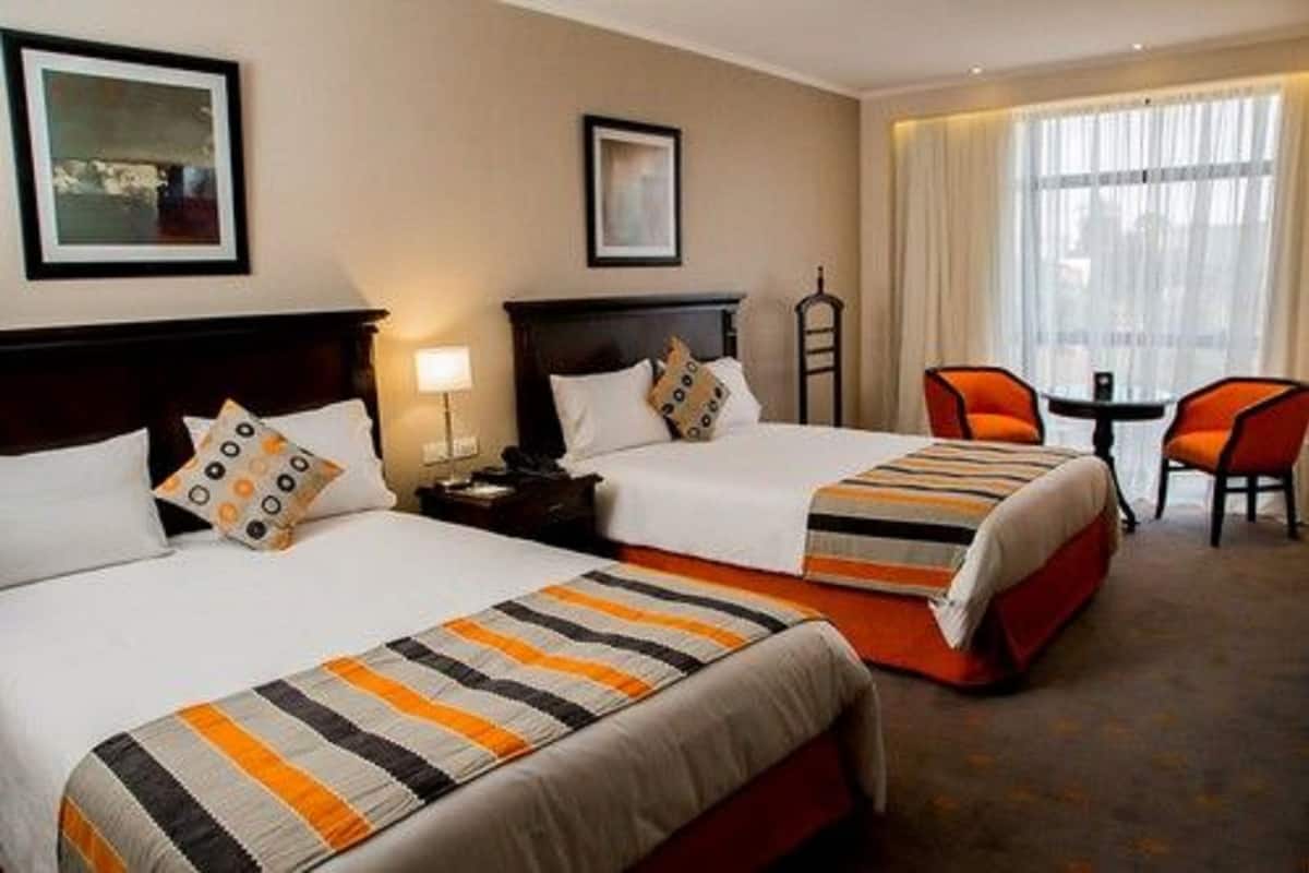 A hotel room with two beds, a small table, and a chair.