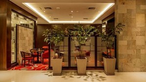 A modern lobby with a glass partition, potted plants, and a seating area. - Carnaval Hotel Casino (Encarnacion)