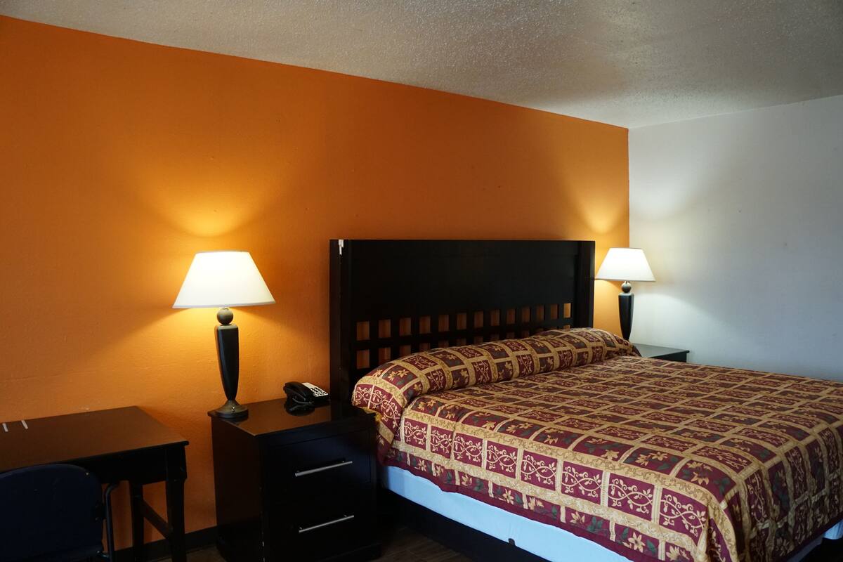 A hotel room with a bed, two bedside tables with lamps, a desk, and a chair.