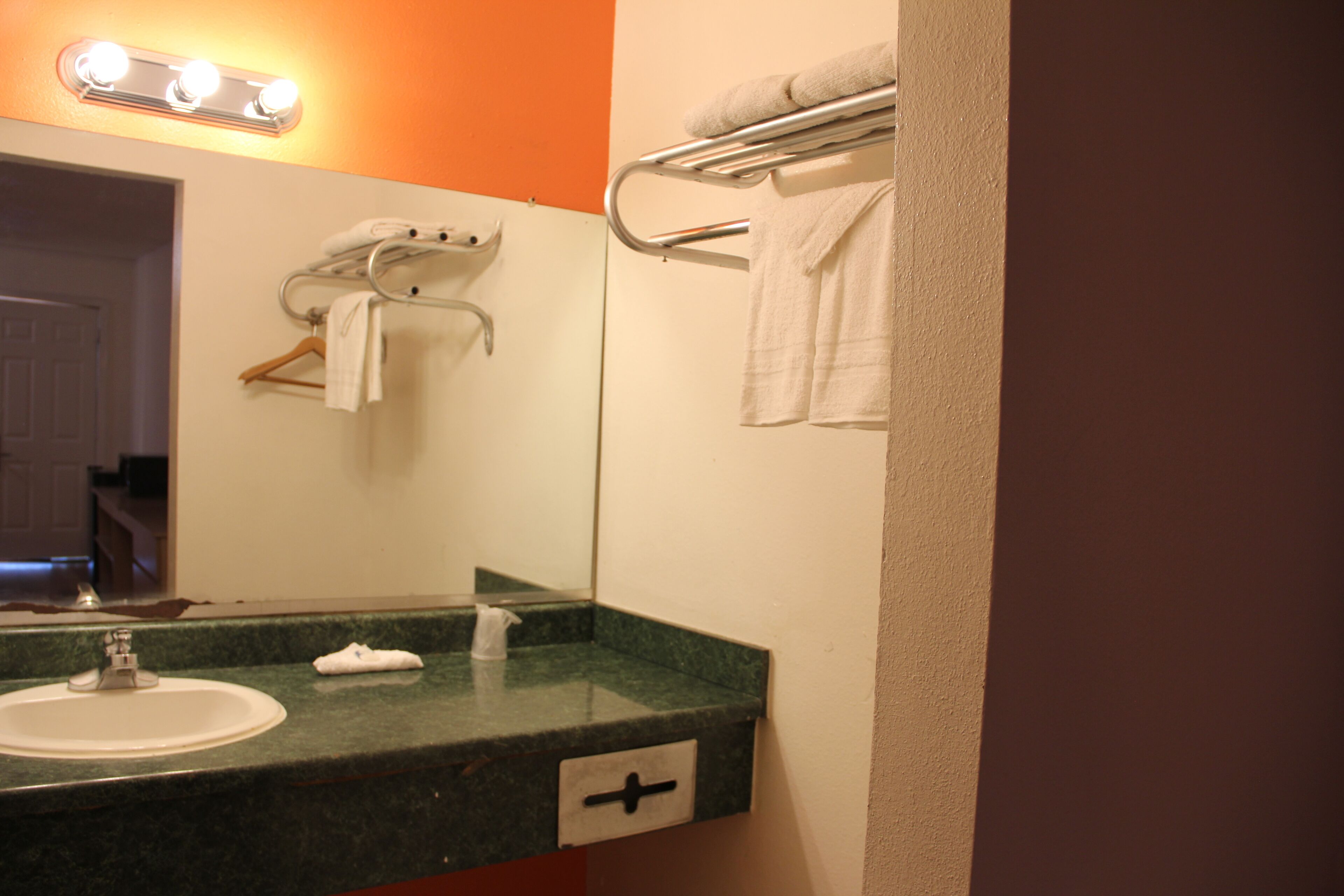 A bathroom with a sink, mirror, towel rack, and a towel hanging on the rack.