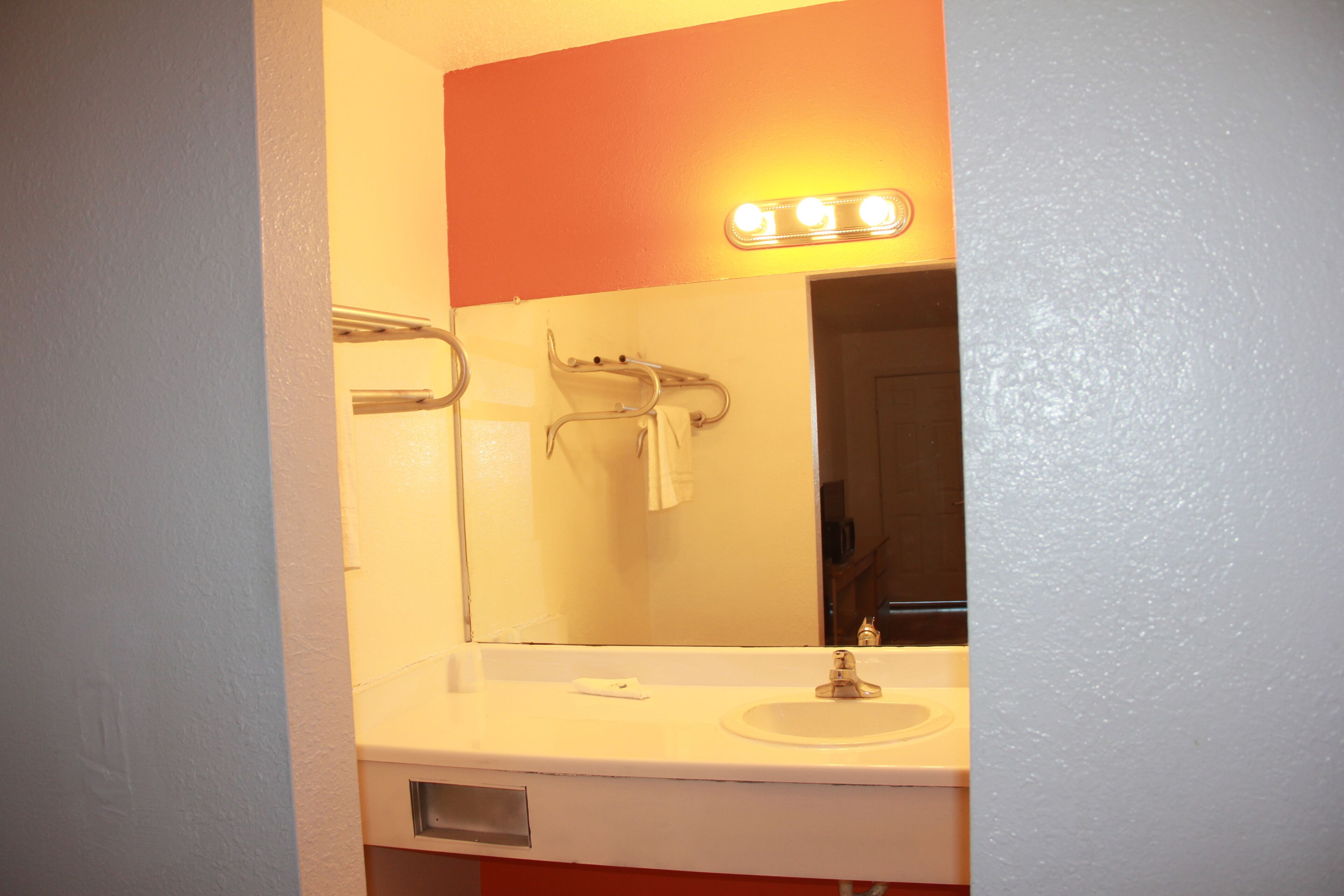 A bathroom with a white sink, a mirror, and a towel rack.