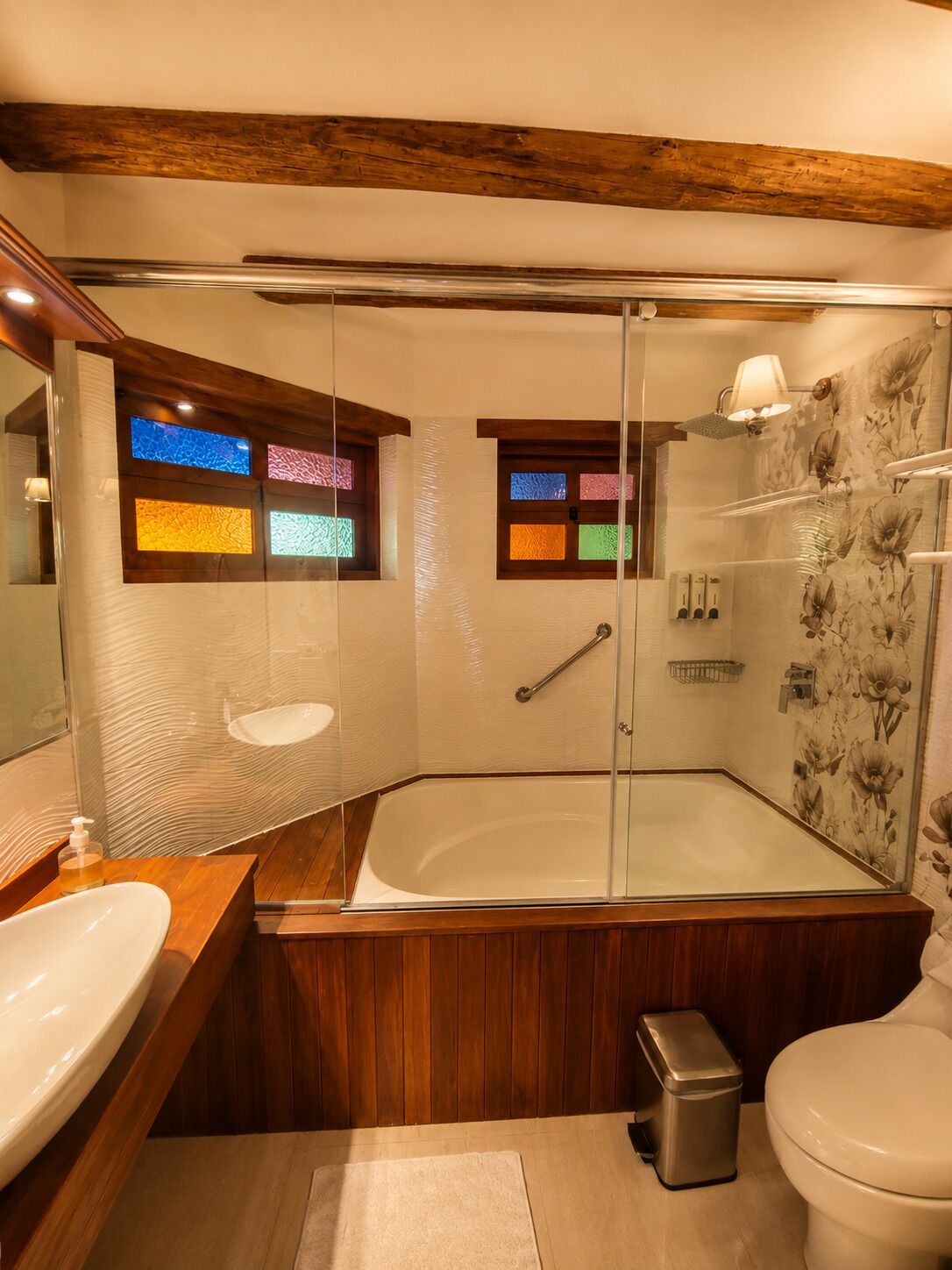 A modern bathroom with a glass-enclosed shower, wooden vanity, and a large bathtub.