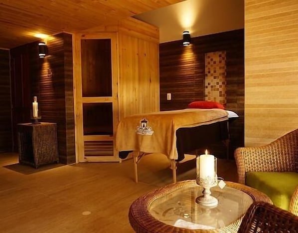 Una habitación acogedora con una cama, una mesita con una vela y una silla de masaje.