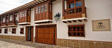 Un edificio tradicional con balcones de madera, grandes puertas de madera y una calle empedrada de piedra.