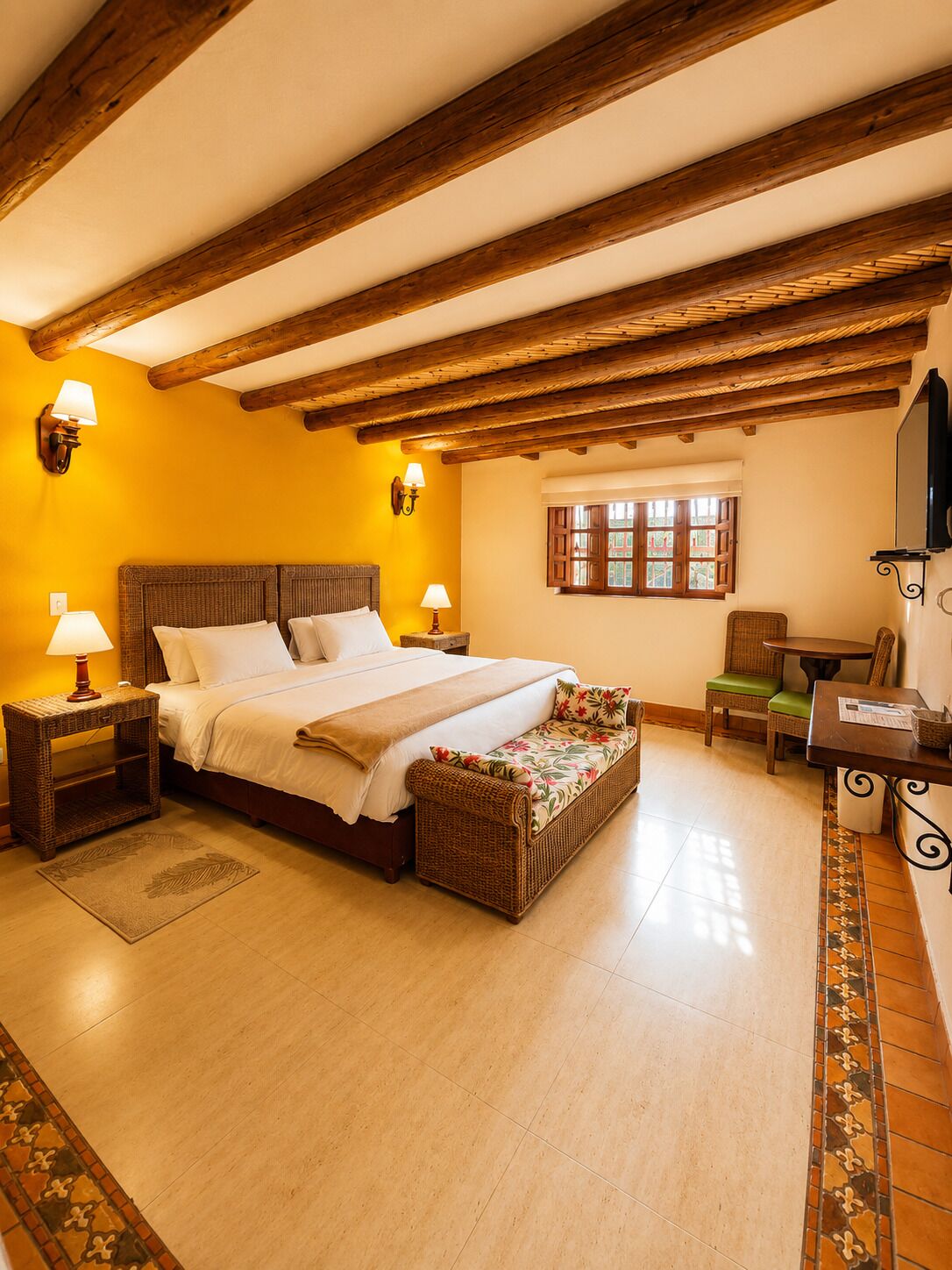 A bedroom with a bed, bedside lamps, a window, a chair, a table, and a television.