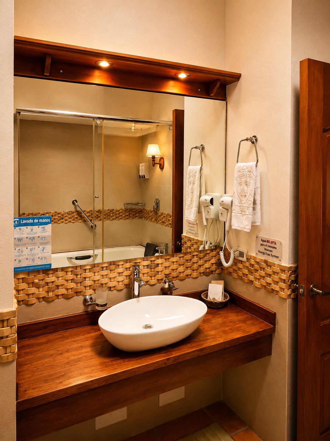 A bathroom with a wooden vanity, a large mirror, a sink, a towel rack, and a hand dryer.