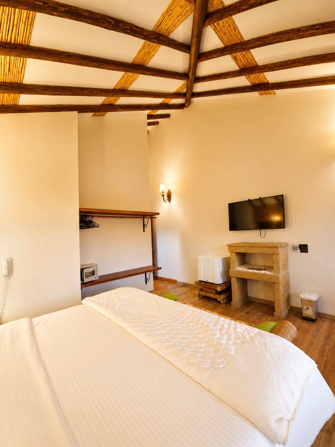 A bedroom with a bed, a television, a small heater, and a wooden shelf.