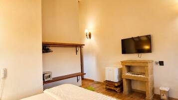 A bedroom with a bed, a television, a small heater, and a wooden shelf.