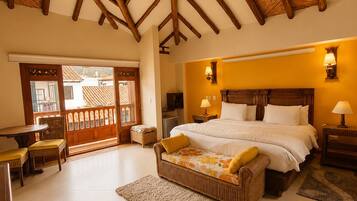 A bedroom with a large bed, wooden ceiling beams, a dining area with chairs, and a view through a door.